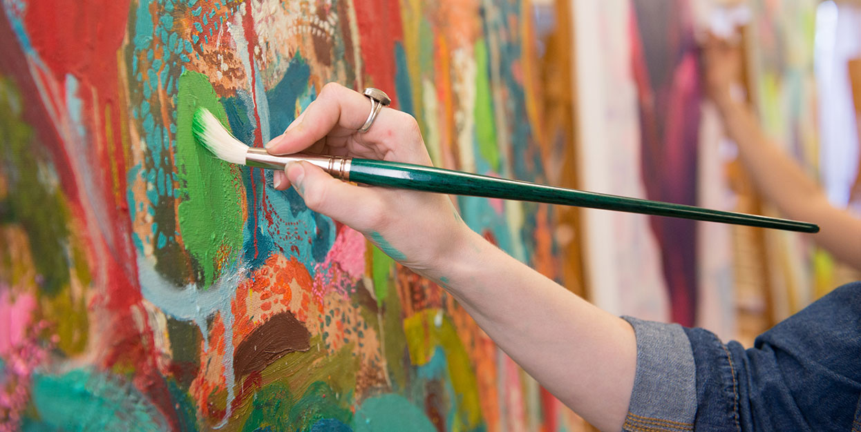 An MCC art student painting in class