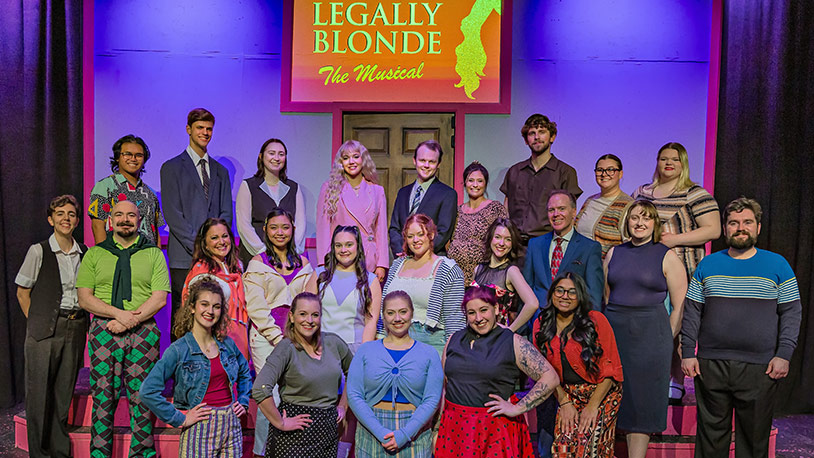 The cast and crew of Legally Blonde the Musical stands in front the theatre in three rows
