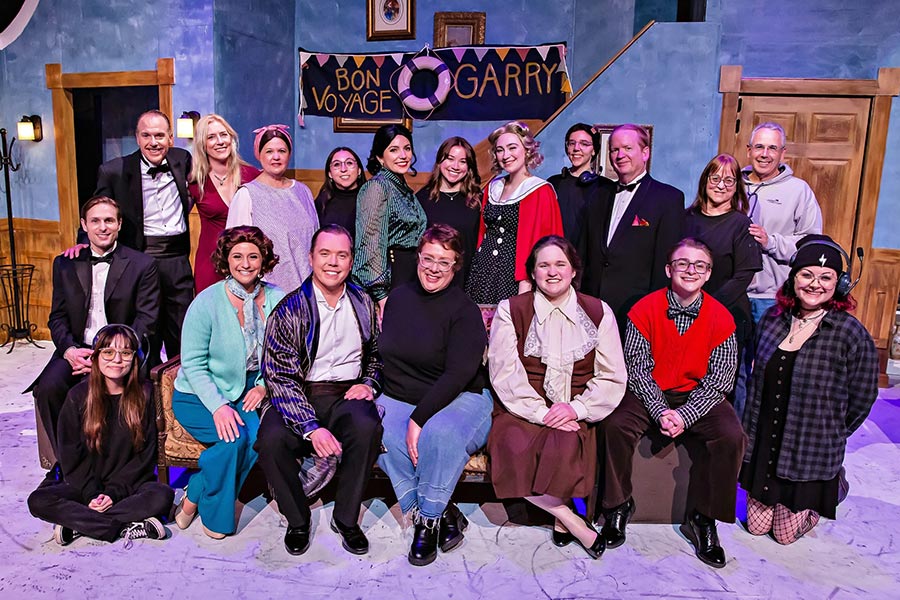 The cast and crew of Present Laughter stands onstage in two rows